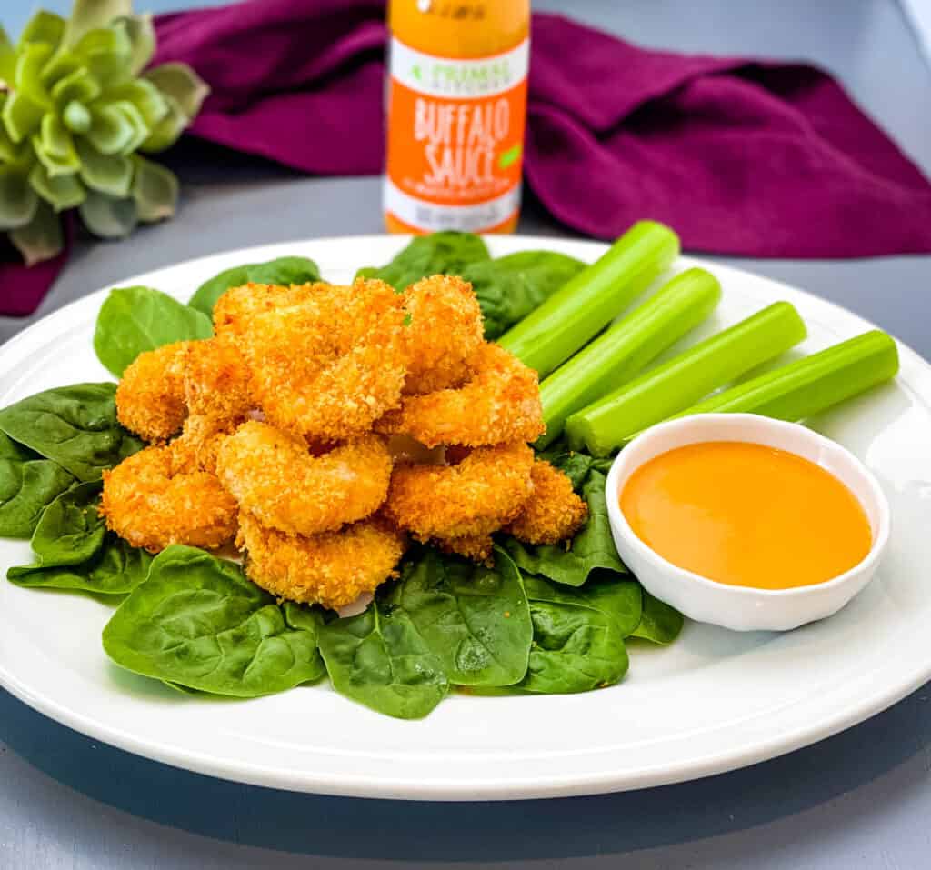 buffalo shrimp on a bed of lettuce with a bowl of buffalo sauce