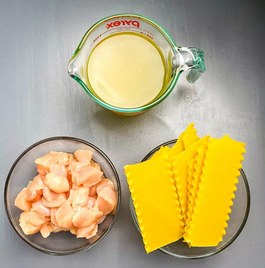 chicken broth, raw chunks of chicken, and lasagna noodles in separate glass bowls