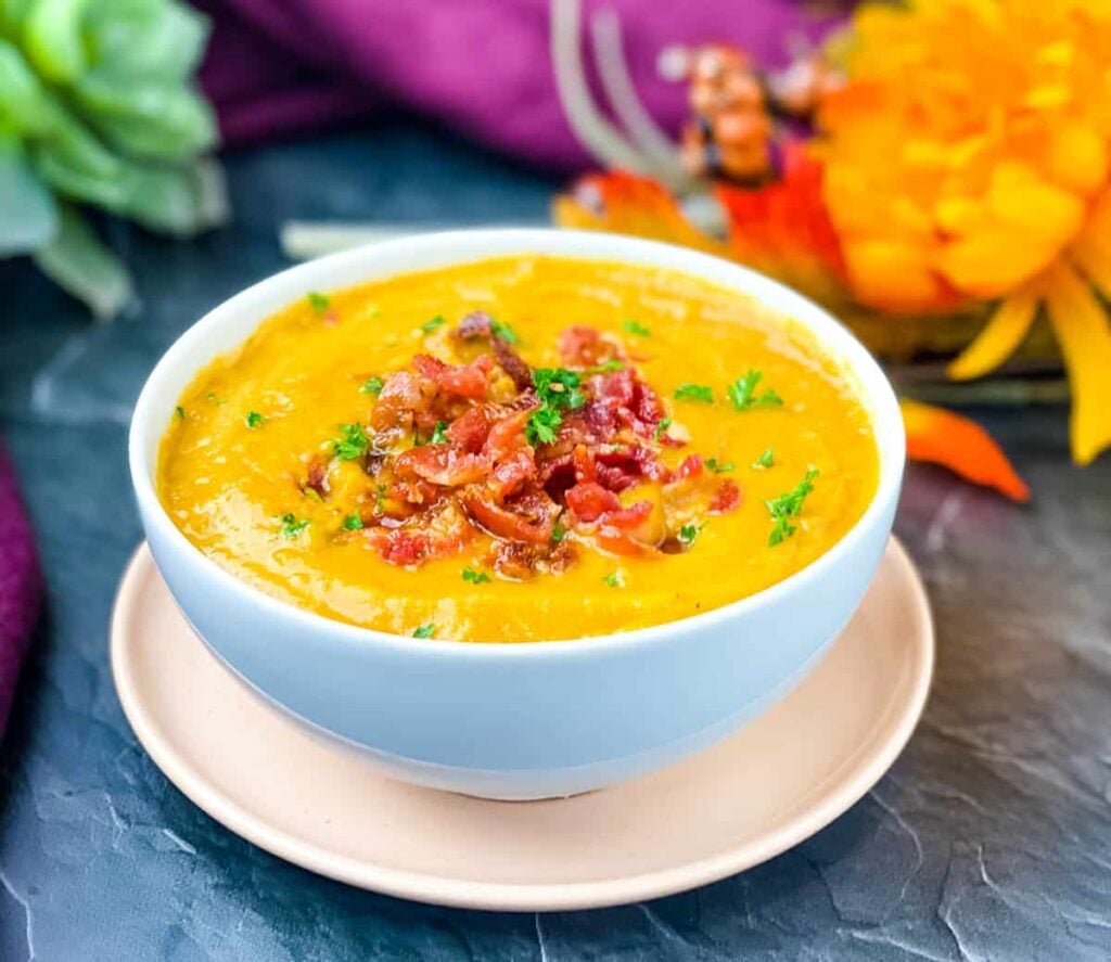 sweet potato soup in a white bowl with chunks of bacon