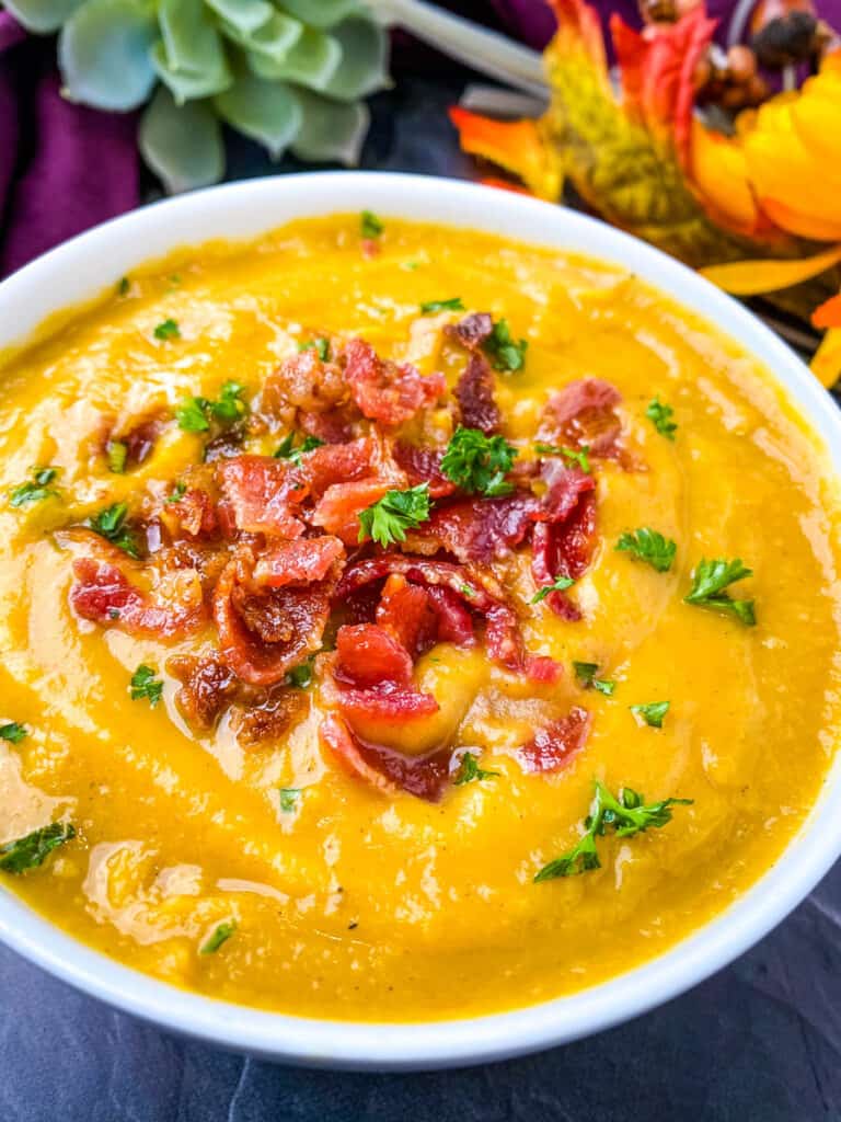 sweet potato soup in a white bowl with chunks of bacon