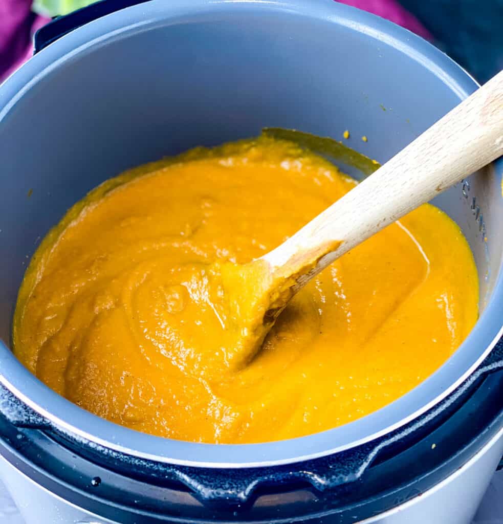 a wooden spoon in a pot of sweet potato soup