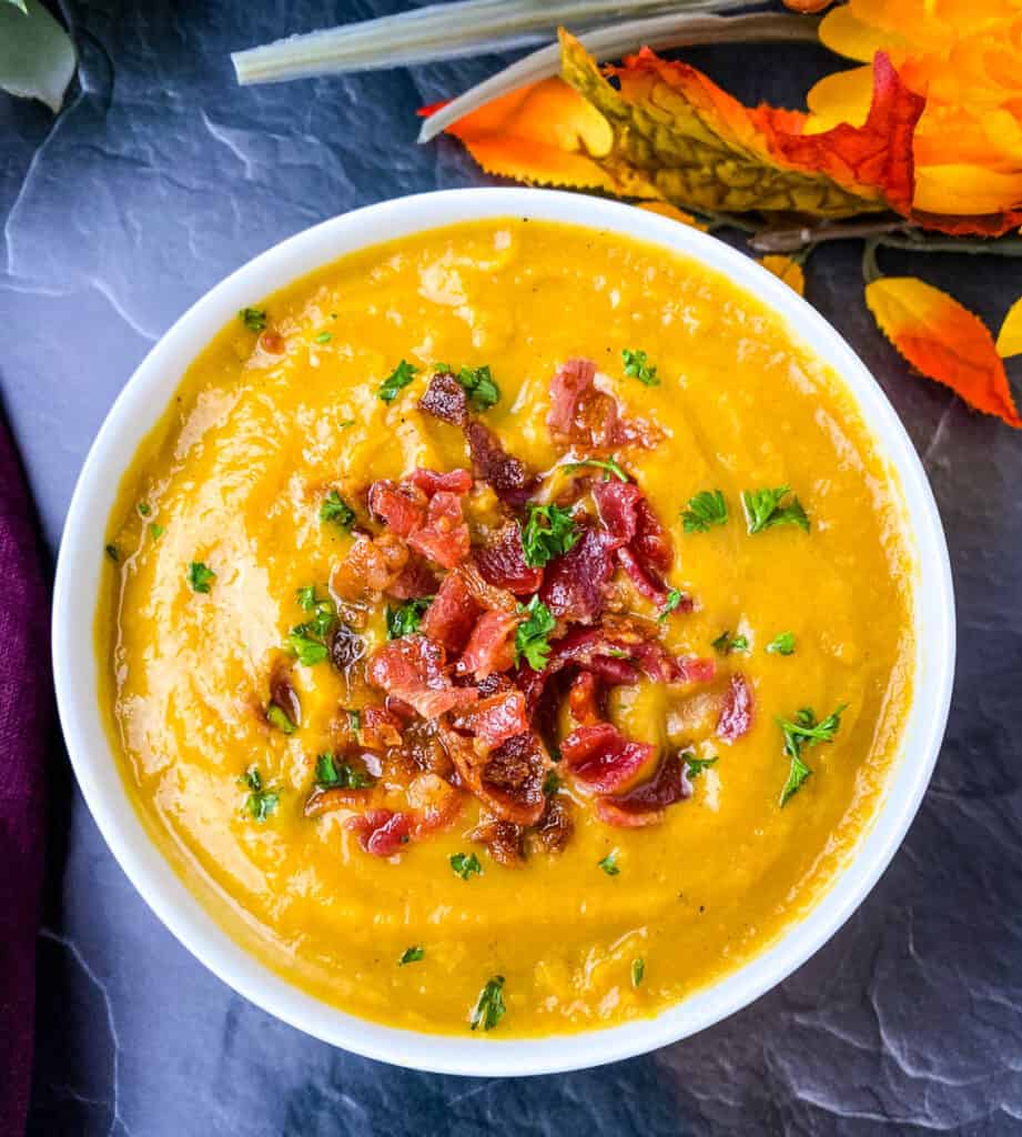 sweet potato soup in a white bowl with chunks of bacon