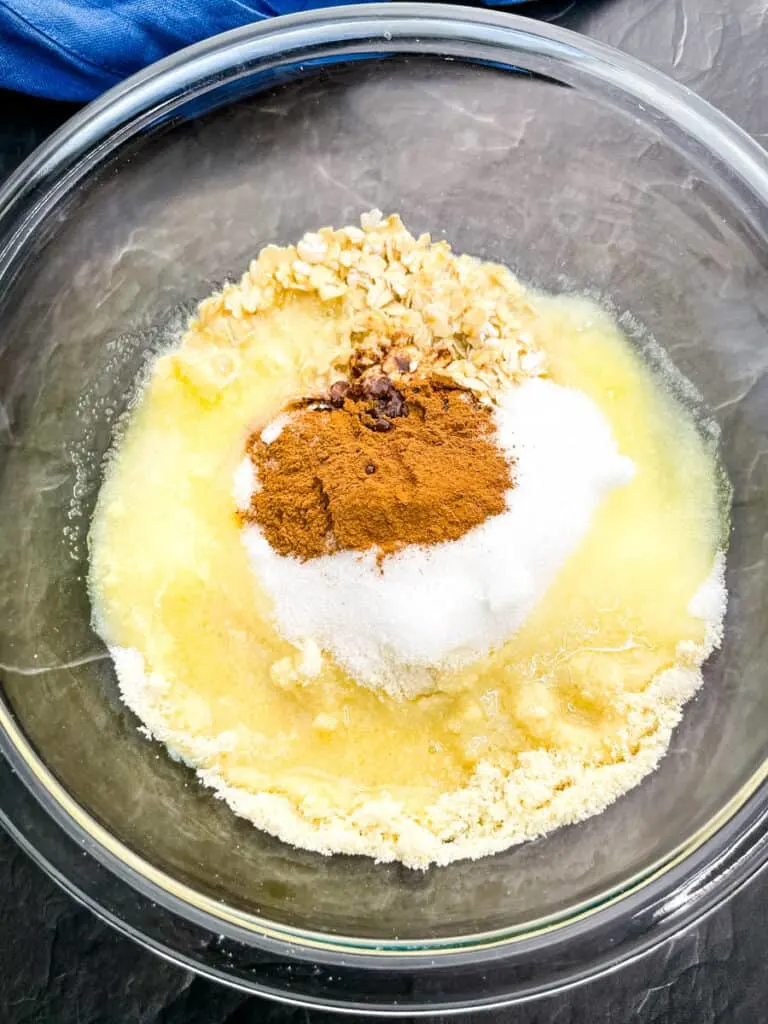 rolled oats, melted butter, cinnamon, and almond flour in a glass bowl for apple pie topping