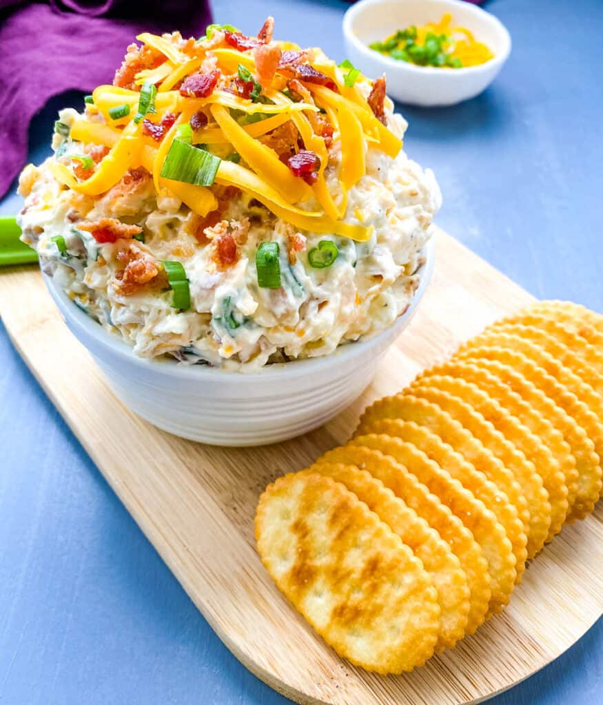 million dollar dip in a white bowl garnished with crackers and celery