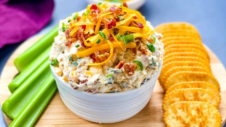 million dollar dip in a white bowl garnished with crackers and celery