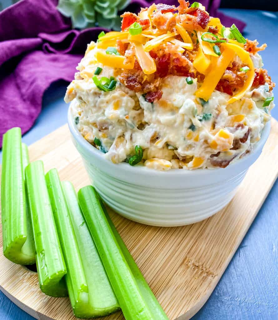 million dollar dip in a white bowl garnished with crackers and celery