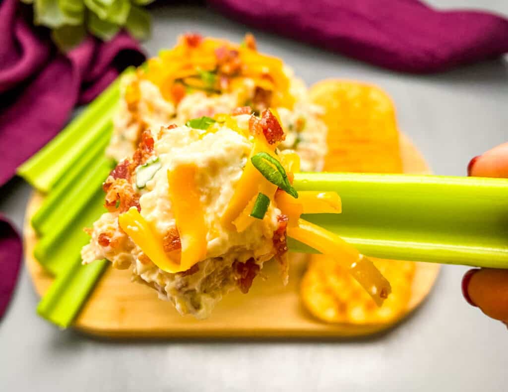 person holding a piece of celery with million dollar dip