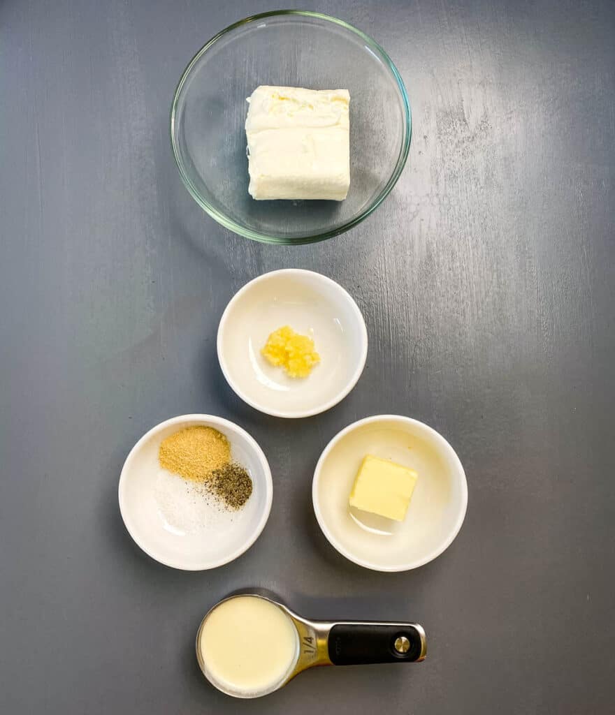 cream cheese garlic, butter, heavy cream, and seasonings in separate bowls on a flat surface