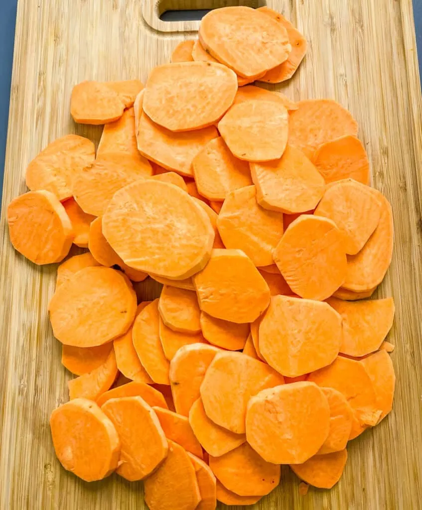 raw and sliced round sweet potatoes on a bamboo cutting board