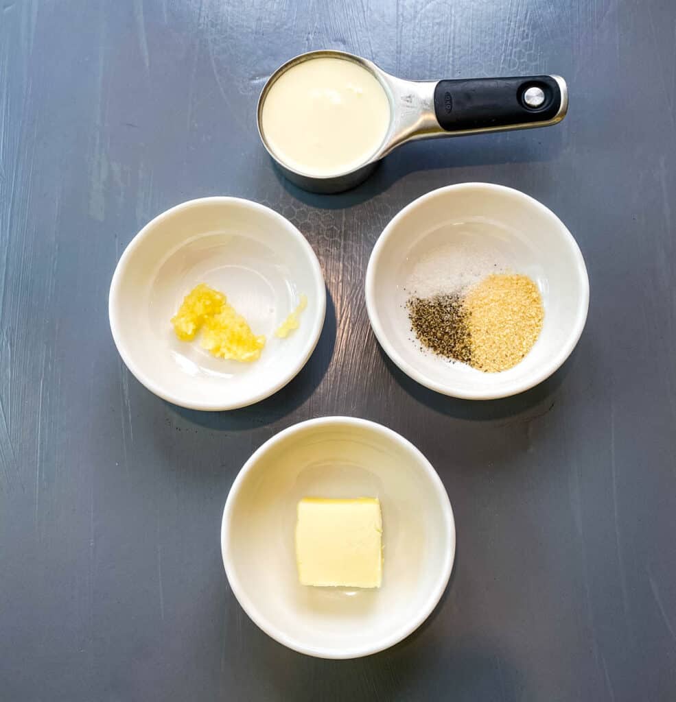 heavy cream, garlic, seasoning, and butter in separate bowls on a flat surface