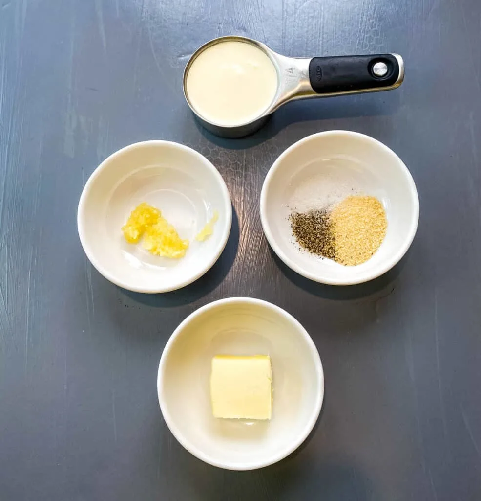 heavy cream, garlic, seasoning, and butter in separate bowls on a flat surface