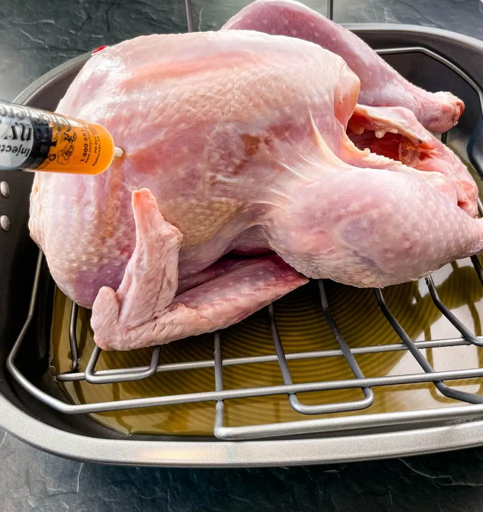raw turkey injected with marinade in a roasting pan