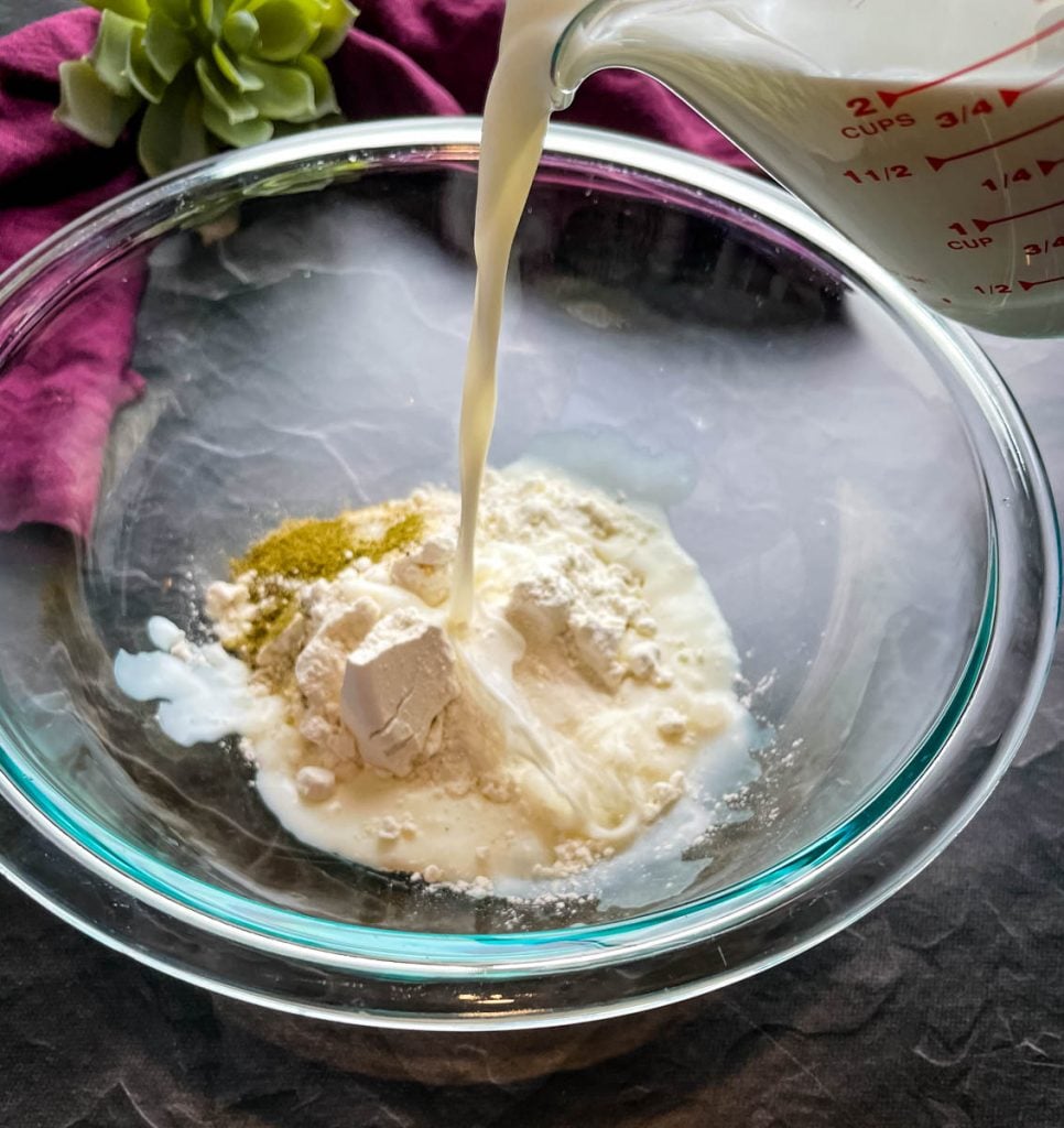 milk poured into a glass bowl with flour and seasoning