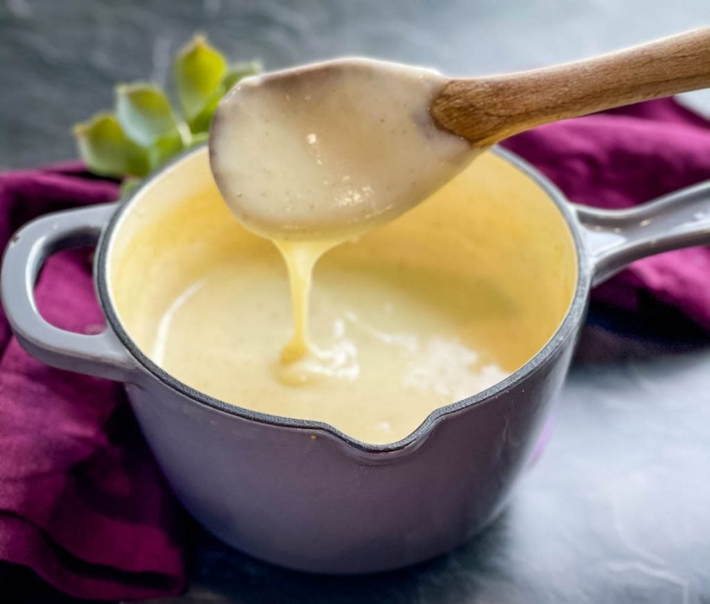 a wooden spoon of homemade cream of chicken soup over a saucepan