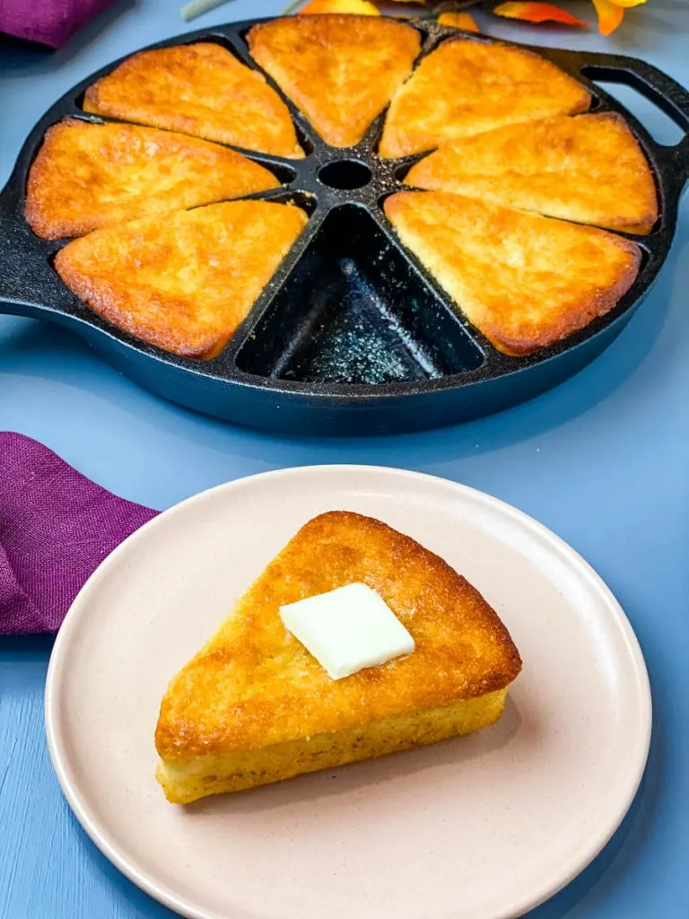 honey cornbread in a cast iron skillet with a slice of cornbread on a plate with butter