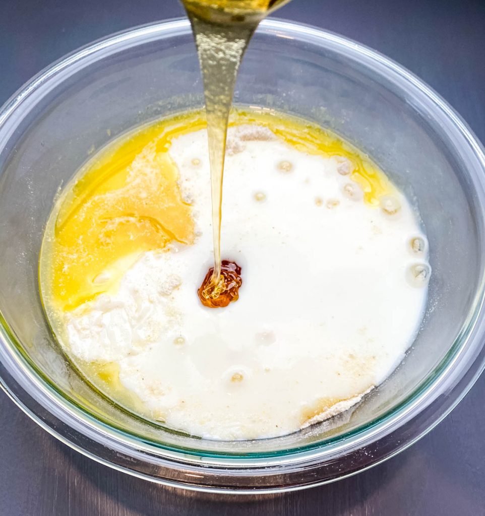 honey poured into a glass bowl with cornbread batter