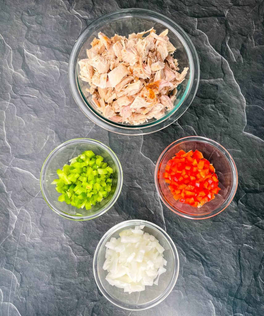 Thanksgiving turkey, chopped green pepper, chopped red peppers, and chopped onions on a flat surface