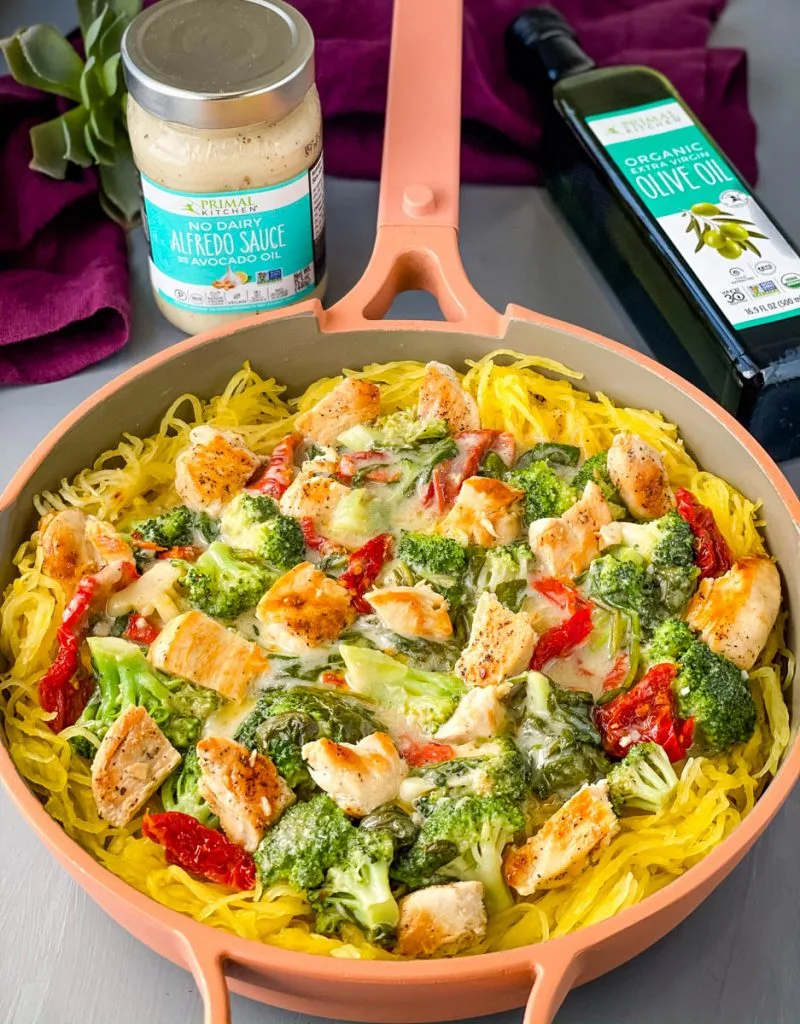 Spaghetti squash chicken alfredo in a pan with broccoli, spinach, and sundried tomatoes