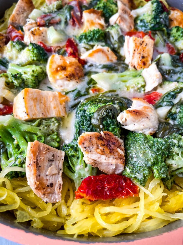 Spaghetti squash chicken alfredo in a pan with broccoli, spinach, and sundried tomatoes