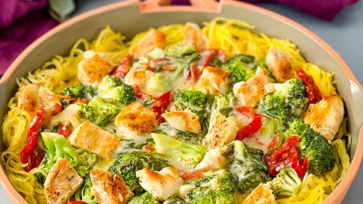 Spaghetti squash chicken alfredo in a pan with broccoli, spinach, and sundried tomatoes