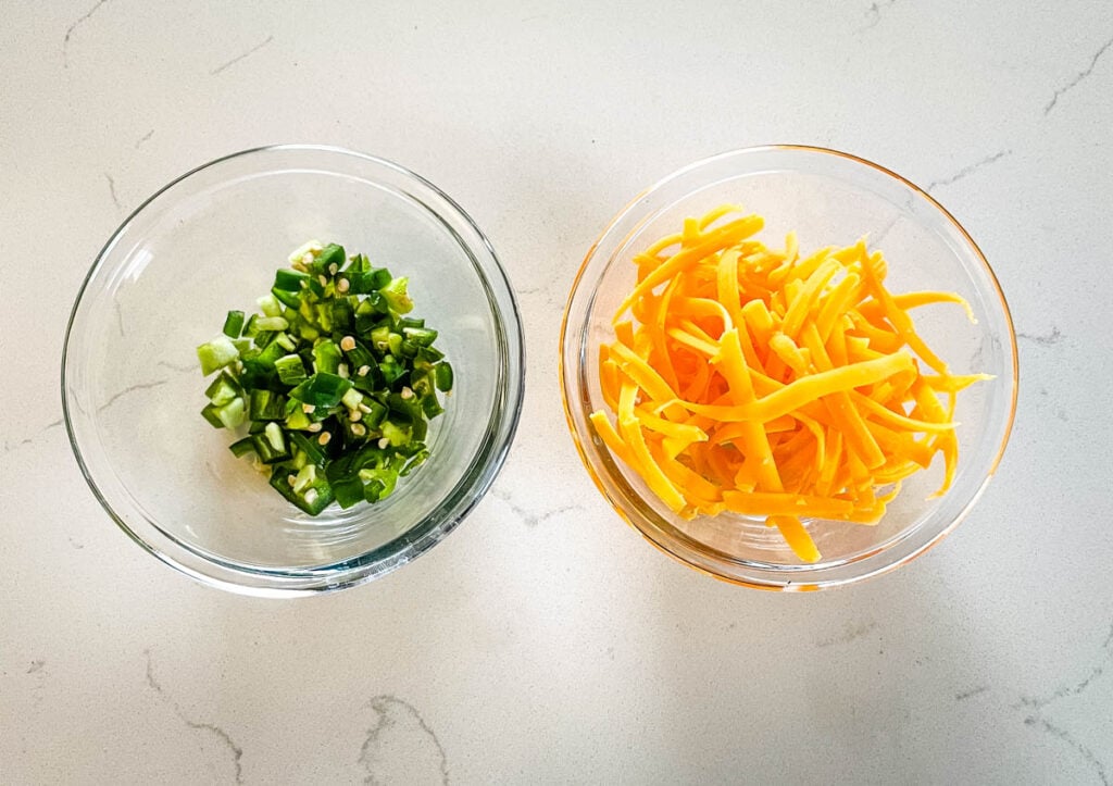 chopped jalapenos and shredded cheddar in separate glas bowls