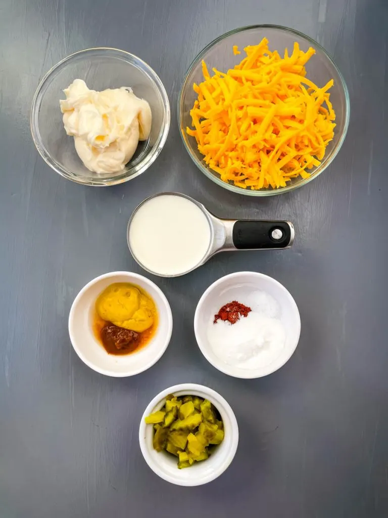 mayo, shredded cheddar, heavy cream, mustard, and chopped pickles in separate glass bowls