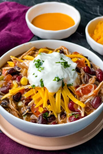 buffalo chicken chili in a white bowl with shredded cheese and sour cream