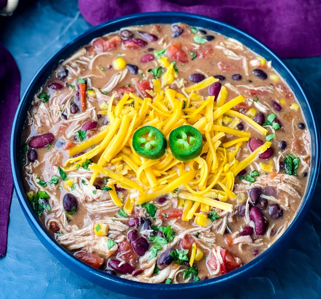 buffalo chicken chili in a blue bowl with shredded cheese and sour cream