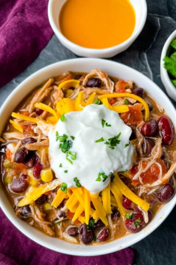 buffalo chicken chili in a white bowl with shredded cheese and sour cream
