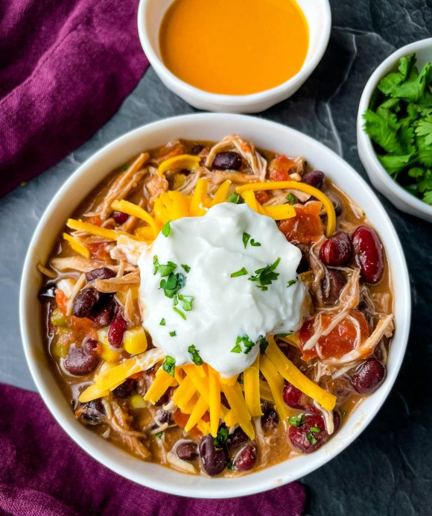 buffalo chicken chili in a white bowl with shredded cheese and sour cream