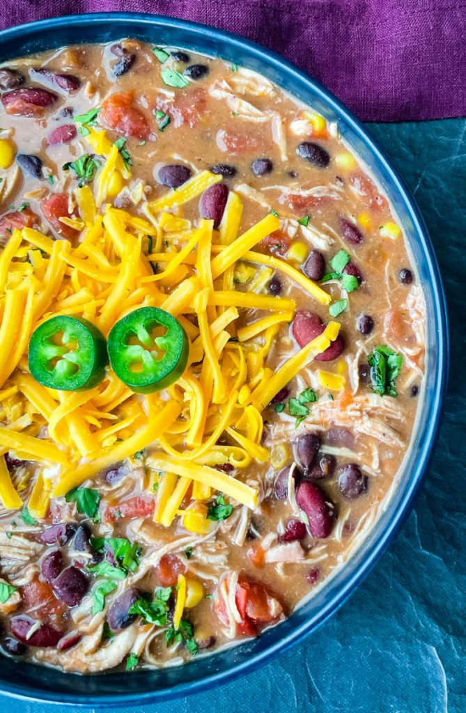 buffalo chicken chili in a blue bowl with shredded cheese and sour cream