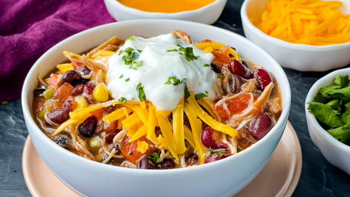 buffalo chicken chili in a white bowl with shredded cheese and sour cream