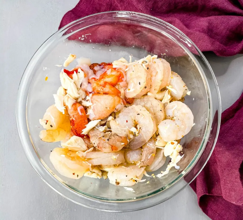 raw seafood shrimp, lobster, and crab in a glass bowl