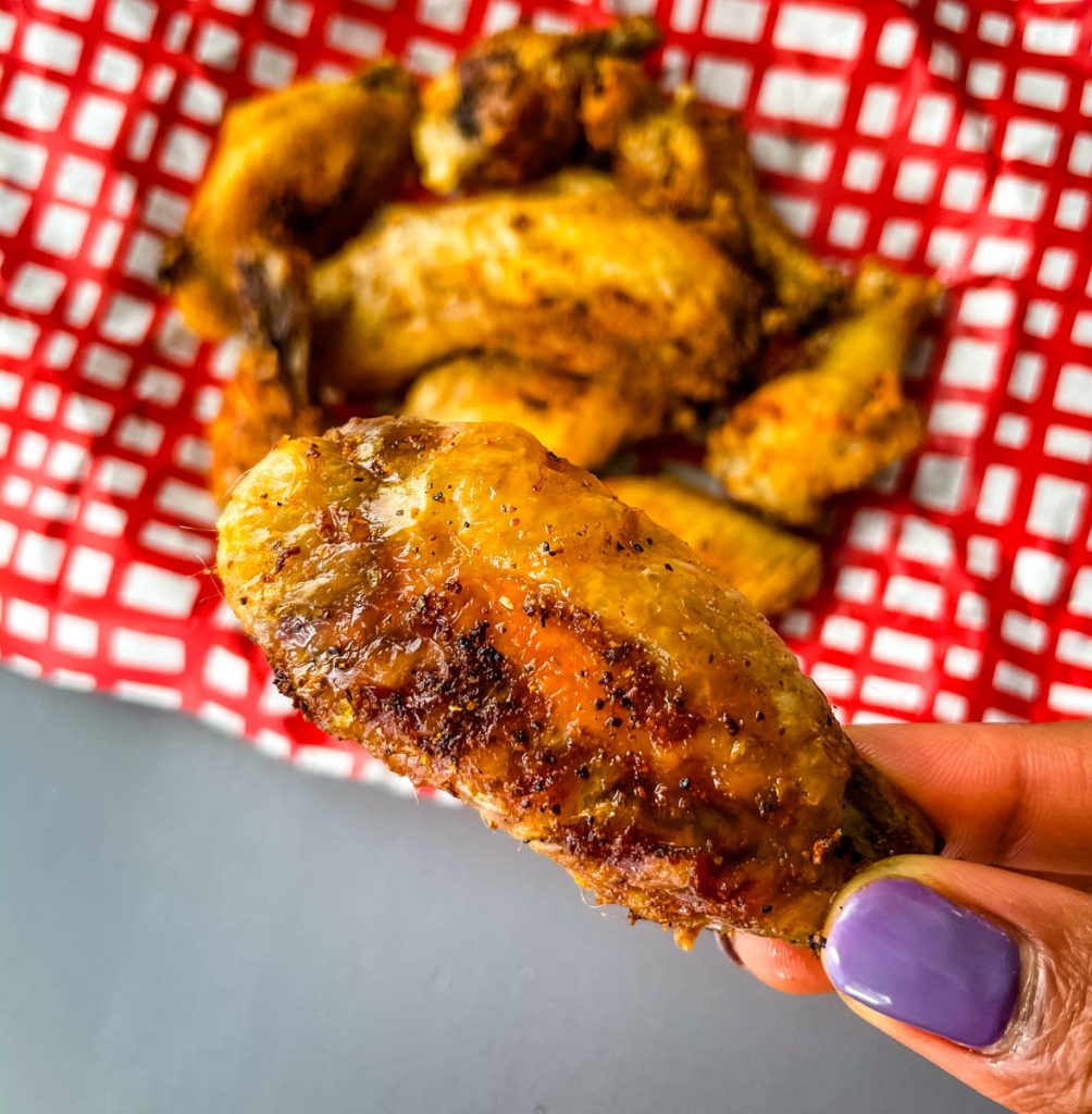person holding air fryer chicken wing