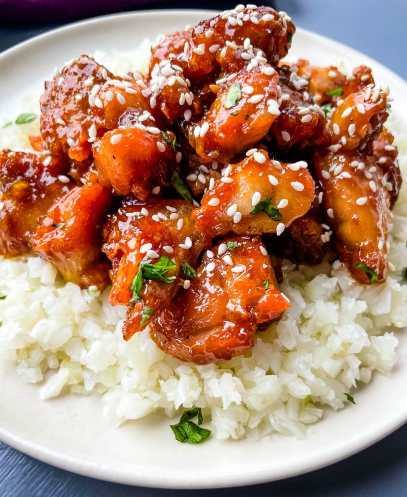 keto low carb orange chicken on a white plate with sesame seeds