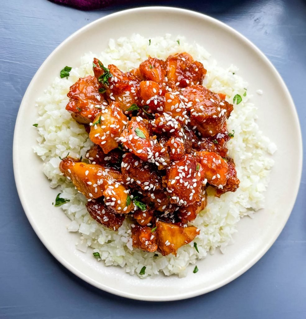 keto low carb orange chicken on a white plate with sesame seeds