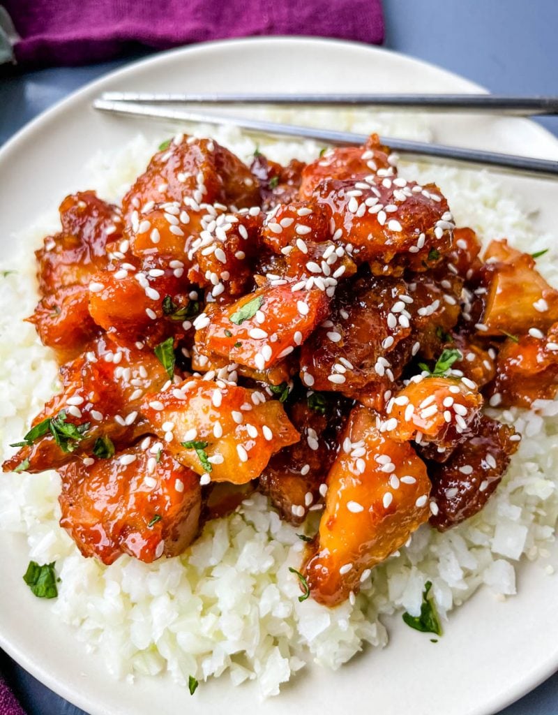 keto low carb orange chicken on a white plate with sesame seeds