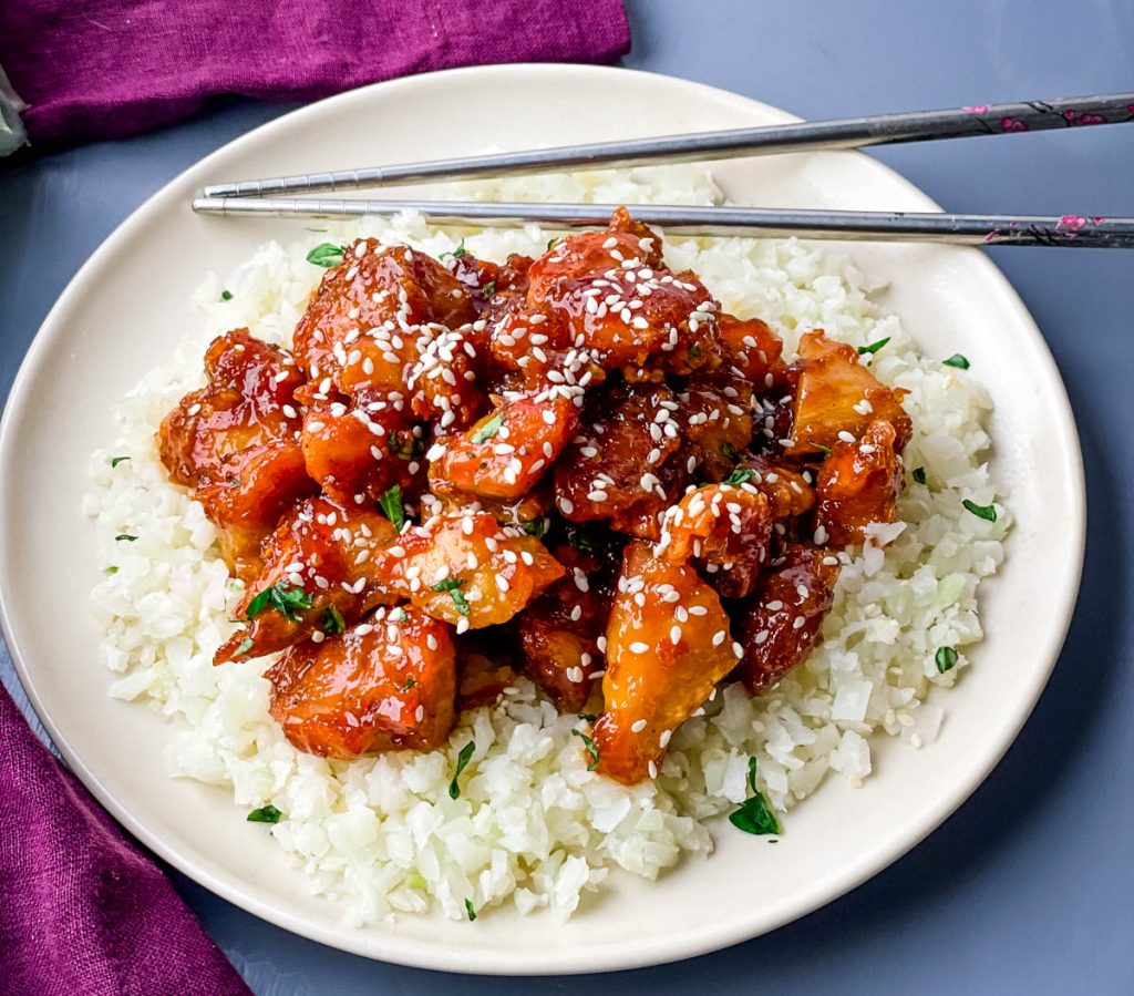 keto low carb orange chicken on a white plate with sesame seeds