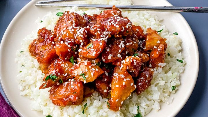 keto low carb orange chicken on a white plate with sesame seeds