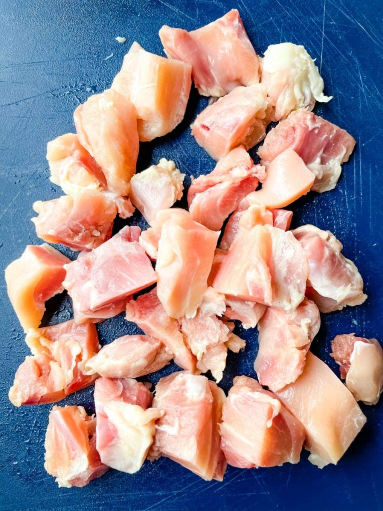 raw chicken thighs sliced on a cutting board