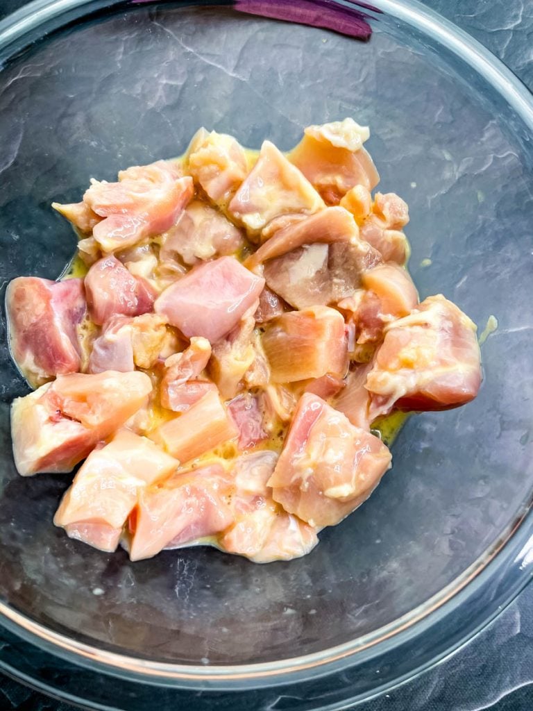 raw chicken thighs in a glass bowl with raw eggs and baking powder
