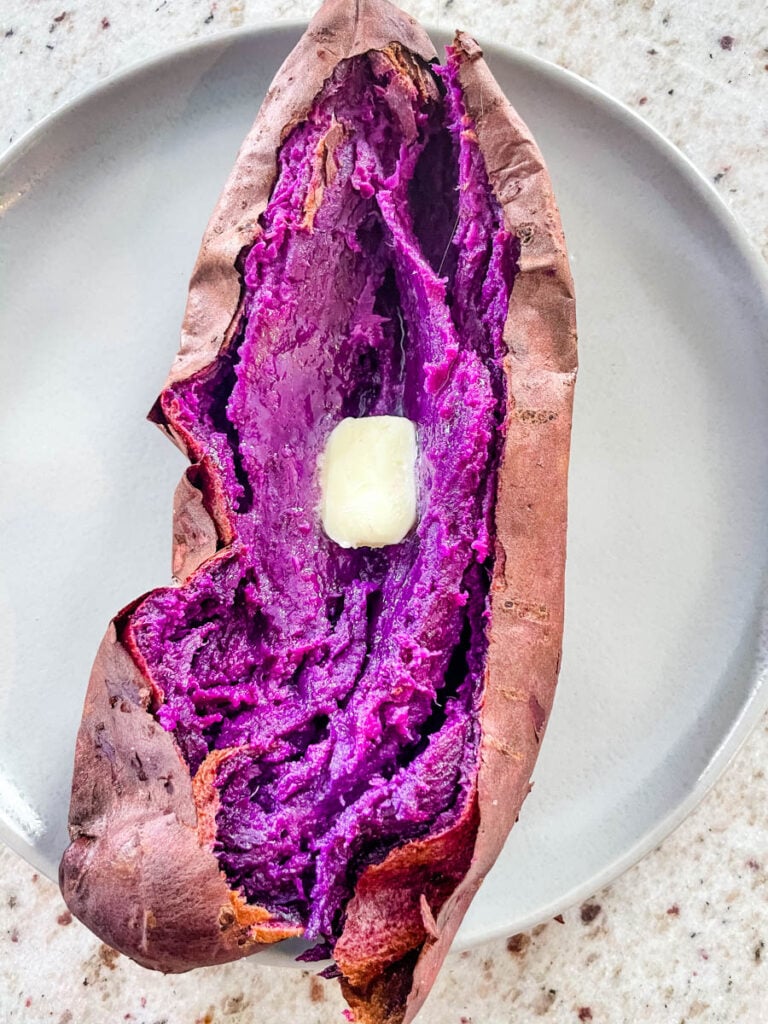 Stokes purple sweet potato fully cooked and sliced open on a plate with buter