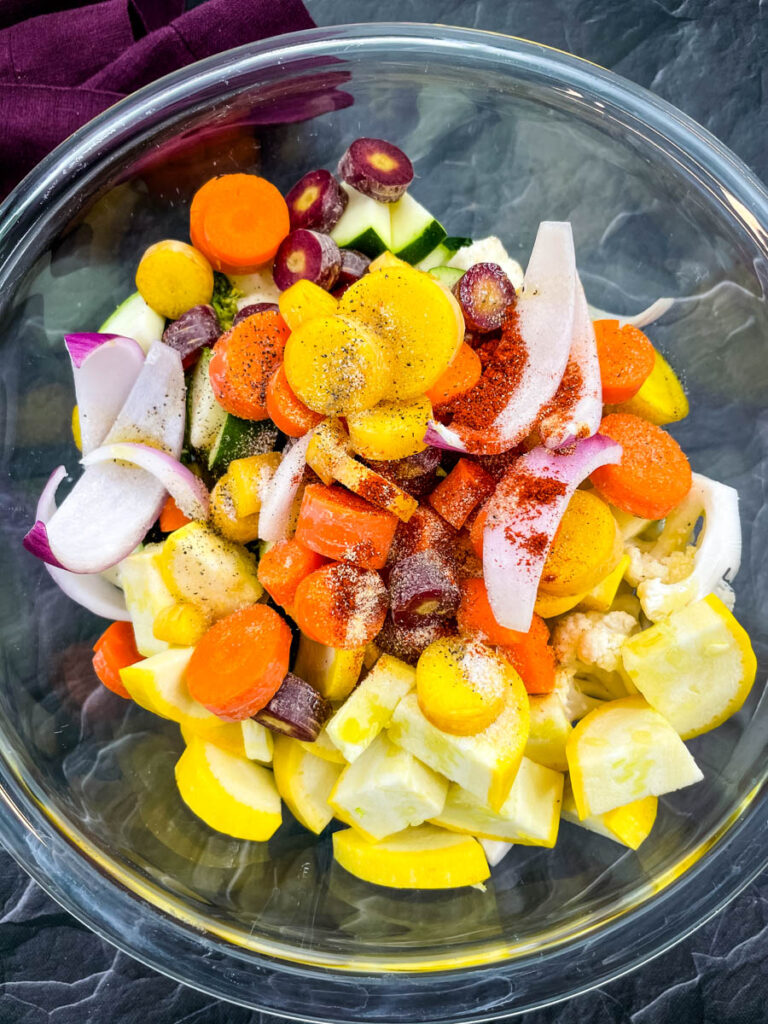 squash, zucchini, onions, carrots, broccoli, and cauliflower in a glass bowl