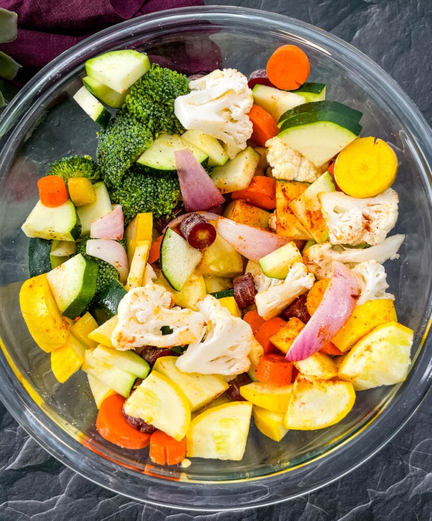 squash, zucchini, onions, carrots, broccoli, and cauliflower in a glass bowl