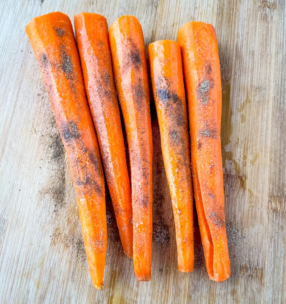 raw carrots seasoned with spices on a cutting board