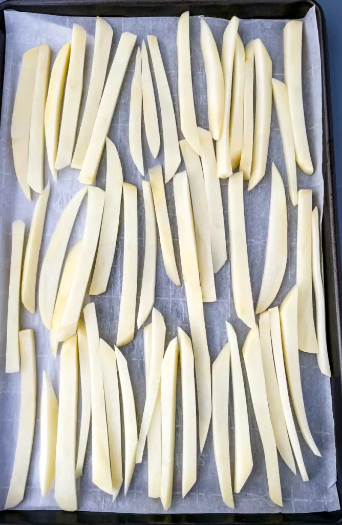 raw sliced potatoes on a sheet pan