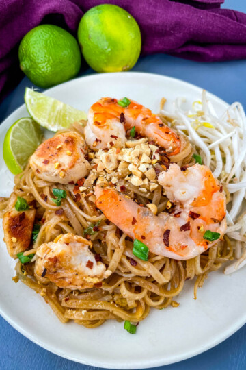 healthy pad thai with chicken, shrimp, bean sprouts, and lime on a white plate
