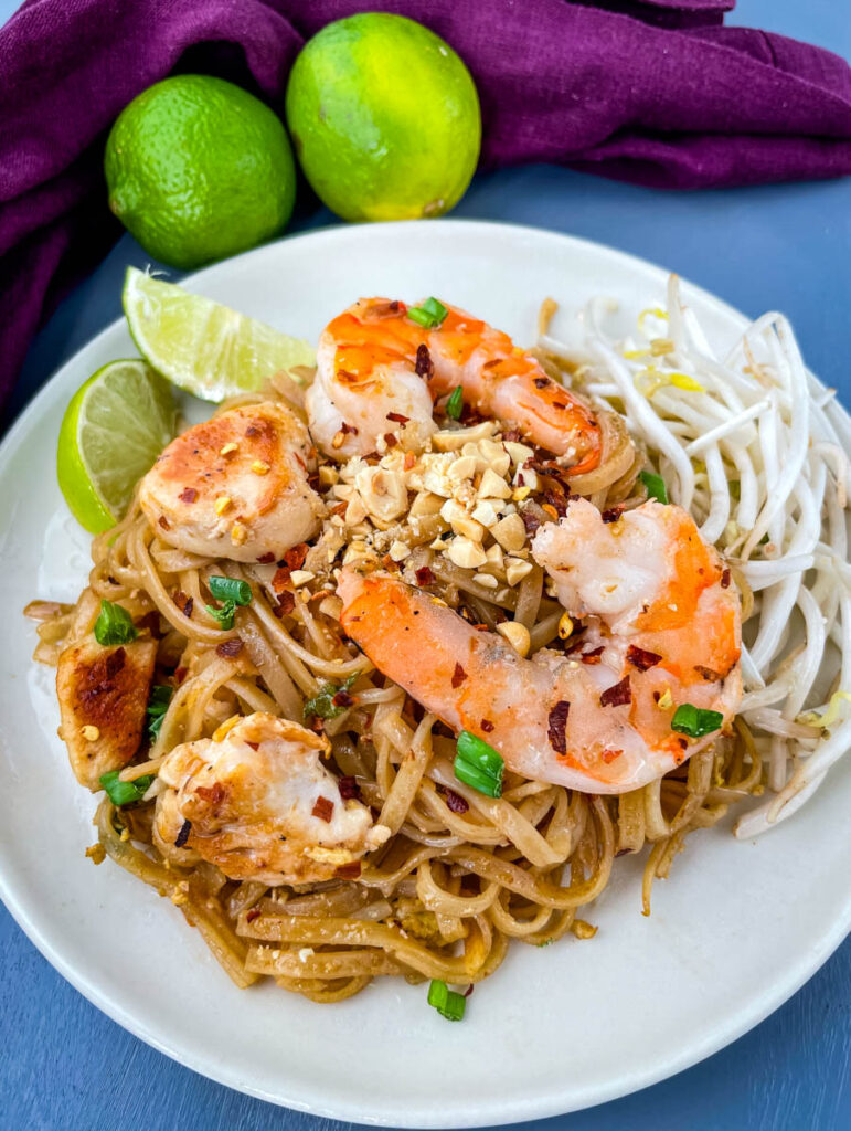 healthy pad thai with chicken, shrimp, bean sprouts, and lime on a white plate