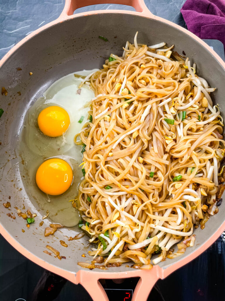 healthy pad thai with chicken, shrimp, bean sprouts, and lime in a pan with raw eggs