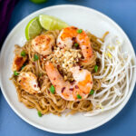 healthy pad thai with chicken, shrimp, bean sprouts, and lime on a white plate